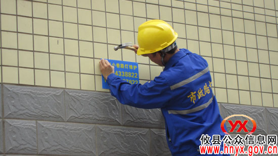 攸县城区小街小巷正在悬挂路灯维护“电话号码牌”
