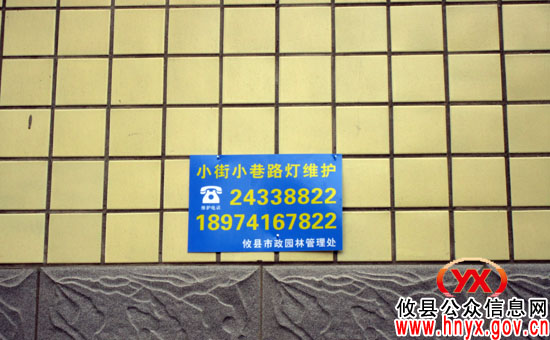攸县城区小街小巷正在悬挂路灯维护“电话号码牌”